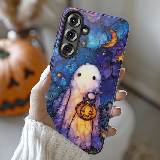 Hand holding a phone case with a ghost and pumpkin design, with pumpkins in the background.